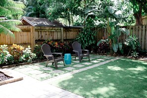 Relax and socialize in this serene outdoor space with a lawn, deck, and lush plants.