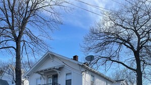 Ein weißes, zweistöckiges Haus mit Balkon, Satellitenschüssel und Garage.