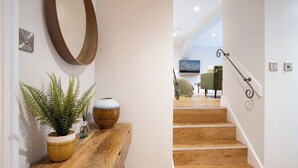A wooden staircase leading to a living area with a green sofa and a painting on the wall. - Spacious Detached property with Waterfall View (Ambleside)