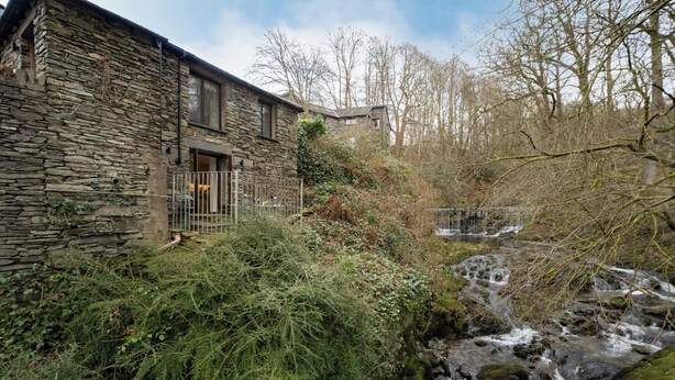 A stone building with a small waterfall in front. - Spacious Detached property with Waterfall View (Ambleside)