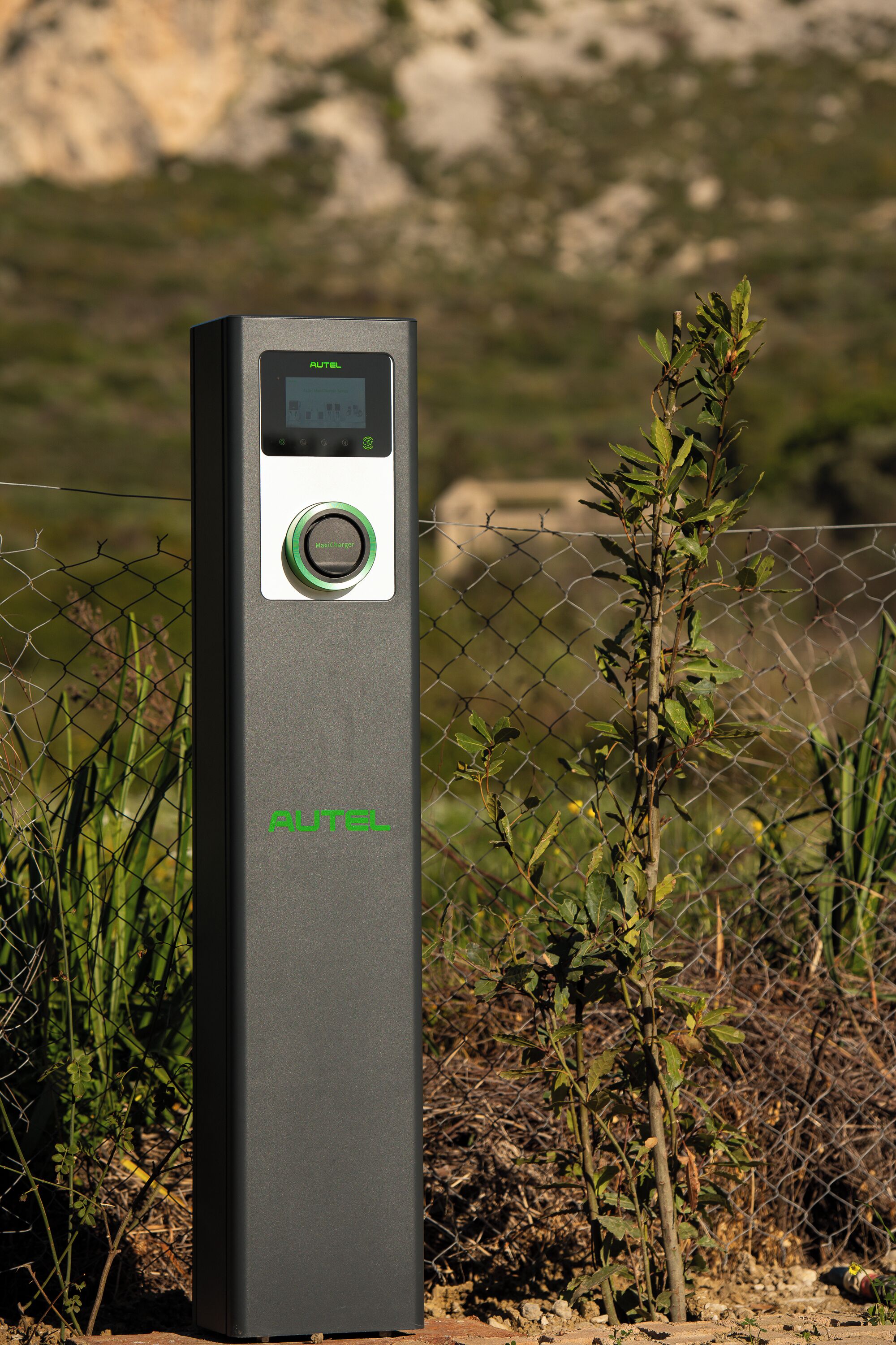 Een zwart buitenbeveiligingsapparaat met een keypad en een groene knop, voorzien van de tekst 