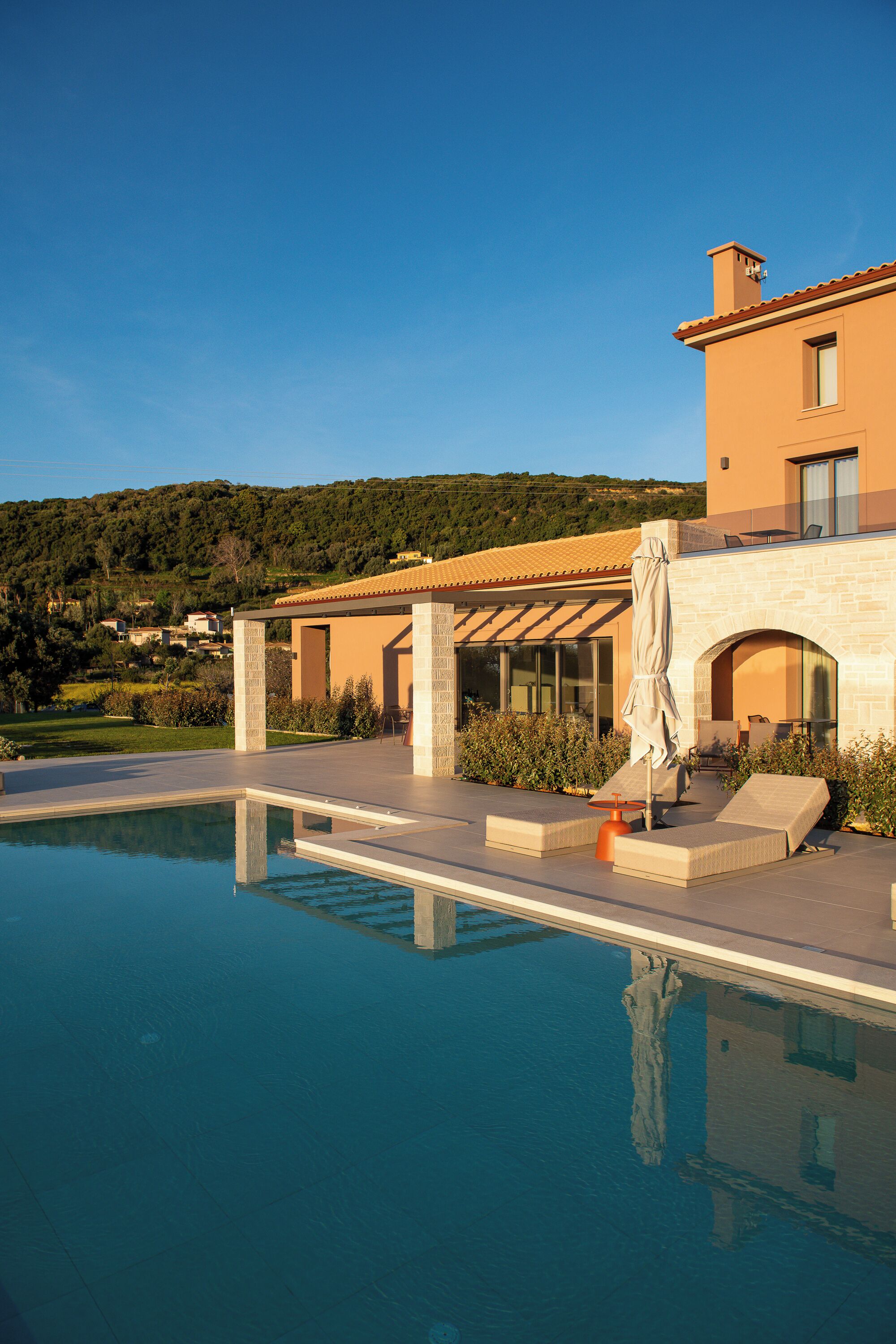Une maison moderne dotée d’une piscine, d’un espace de détente extérieur et offrant une vue sur le paysage environnant.
