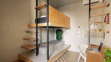 Ein kleines Zimmer mit Etagenbett, Schreibtisch, Laptop und Stuhl.