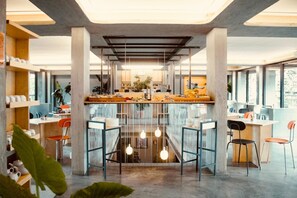 A modern cafe with a central bar, multiple seating areas, and large windows. - 'Re-Dama Hostel (Florence)
