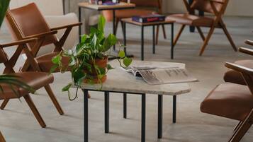Un área de estar moderna con sillones de cuero, una mesa de fútbol y una mesa baja con una planta.