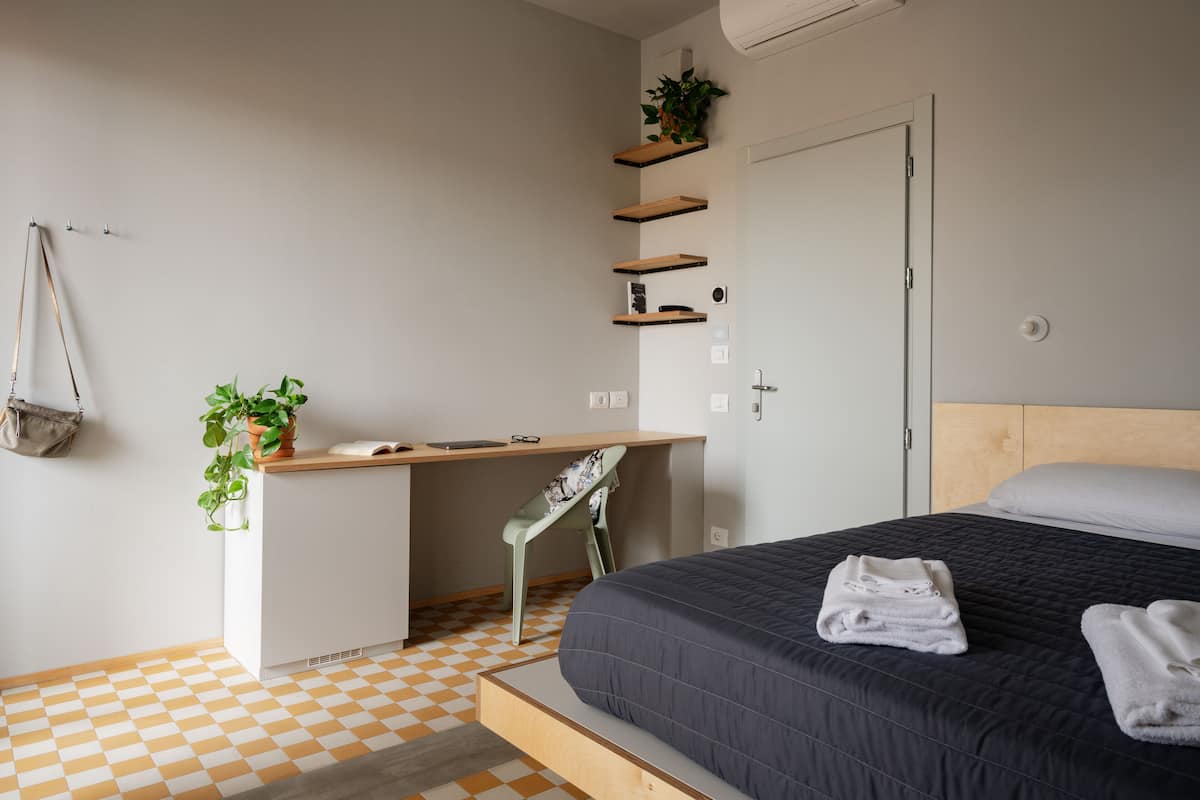 A bedroom with a bed, a desk, and shelves.