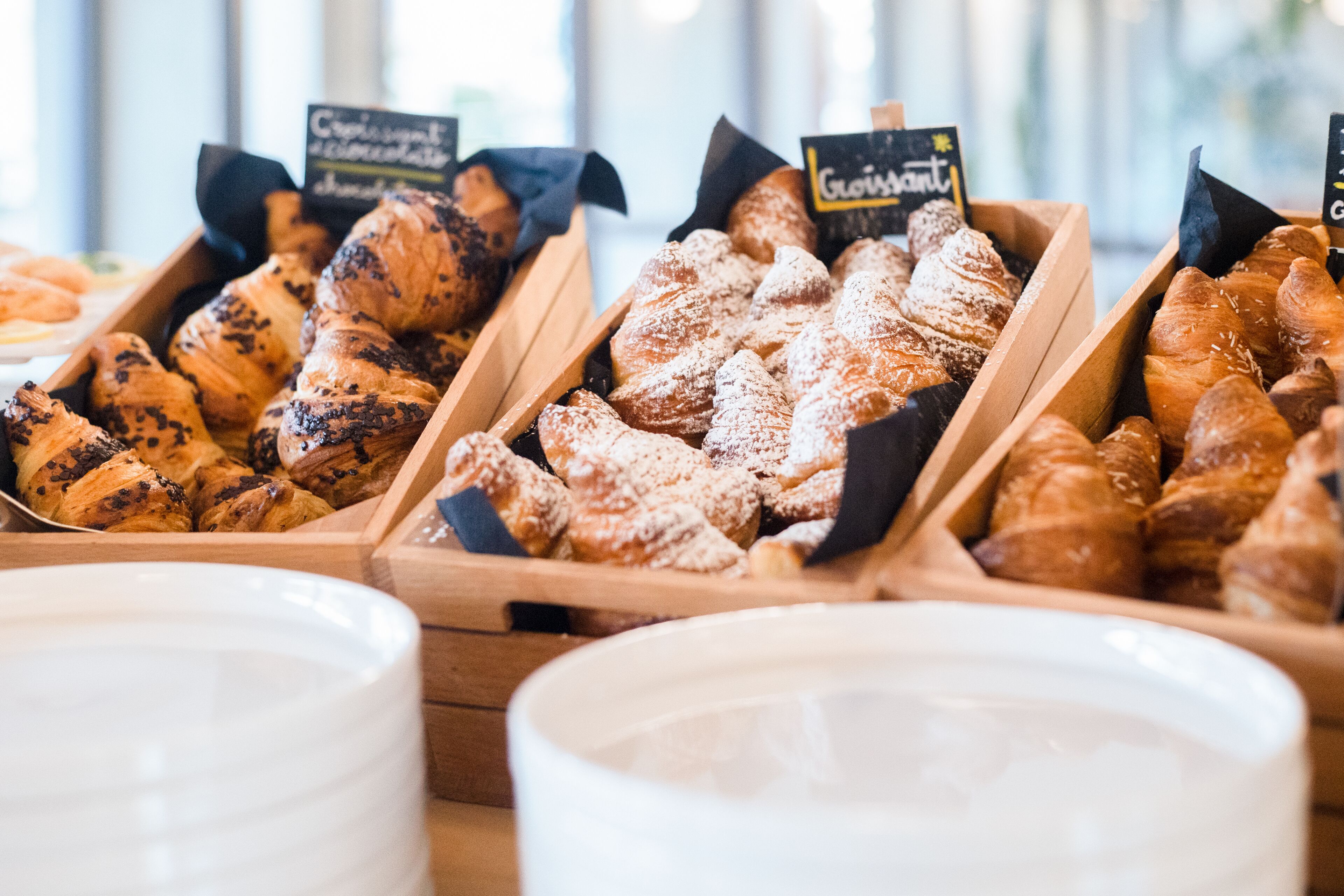 Una vitrina de panadería con diversos tipos de pasteles en cajas de madera, cada una con un nombre.