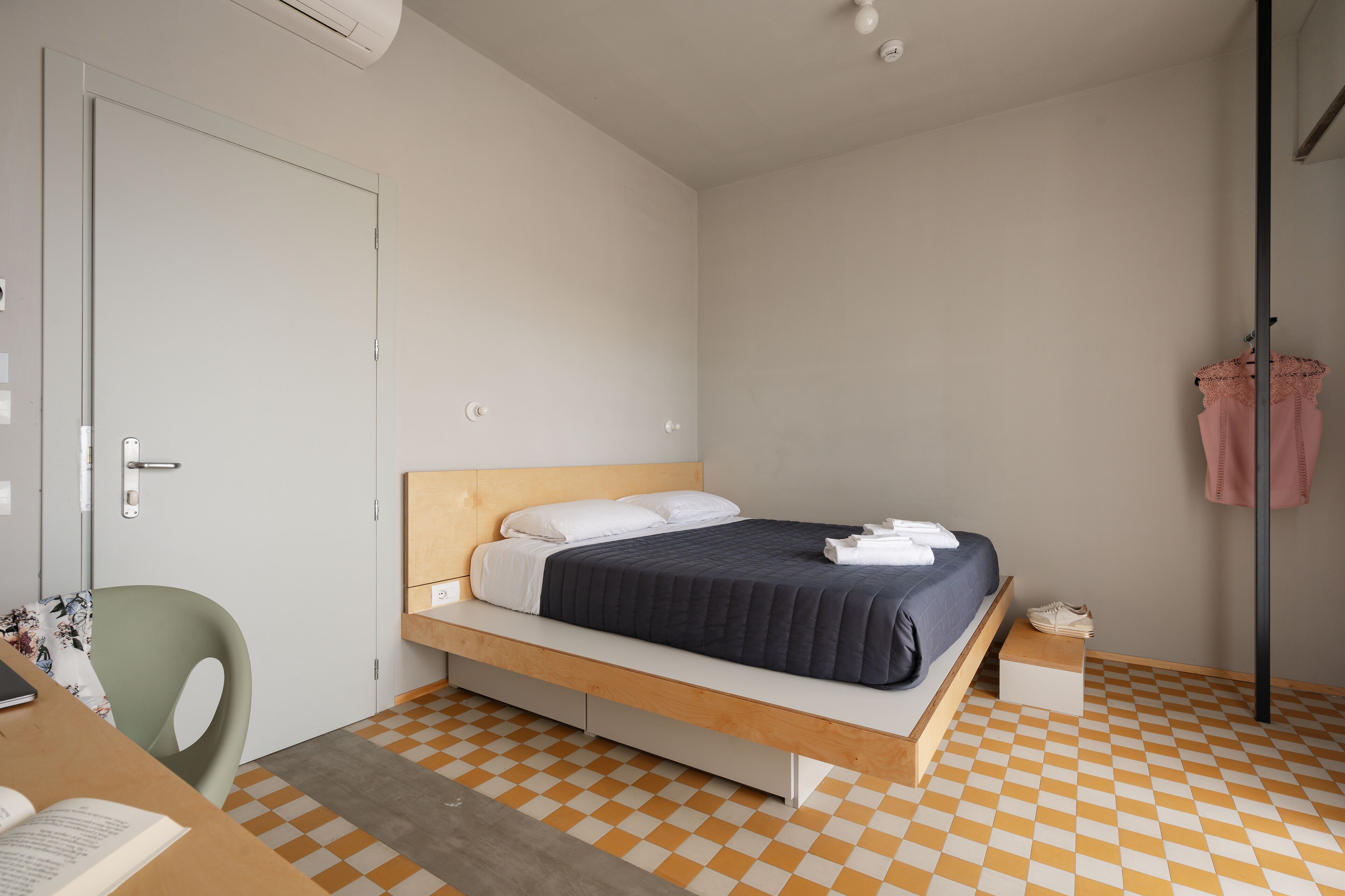 A bedroom with a bed, a desk, and a chair.