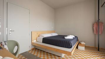 A bedroom with a bed, a desk, and a chair.