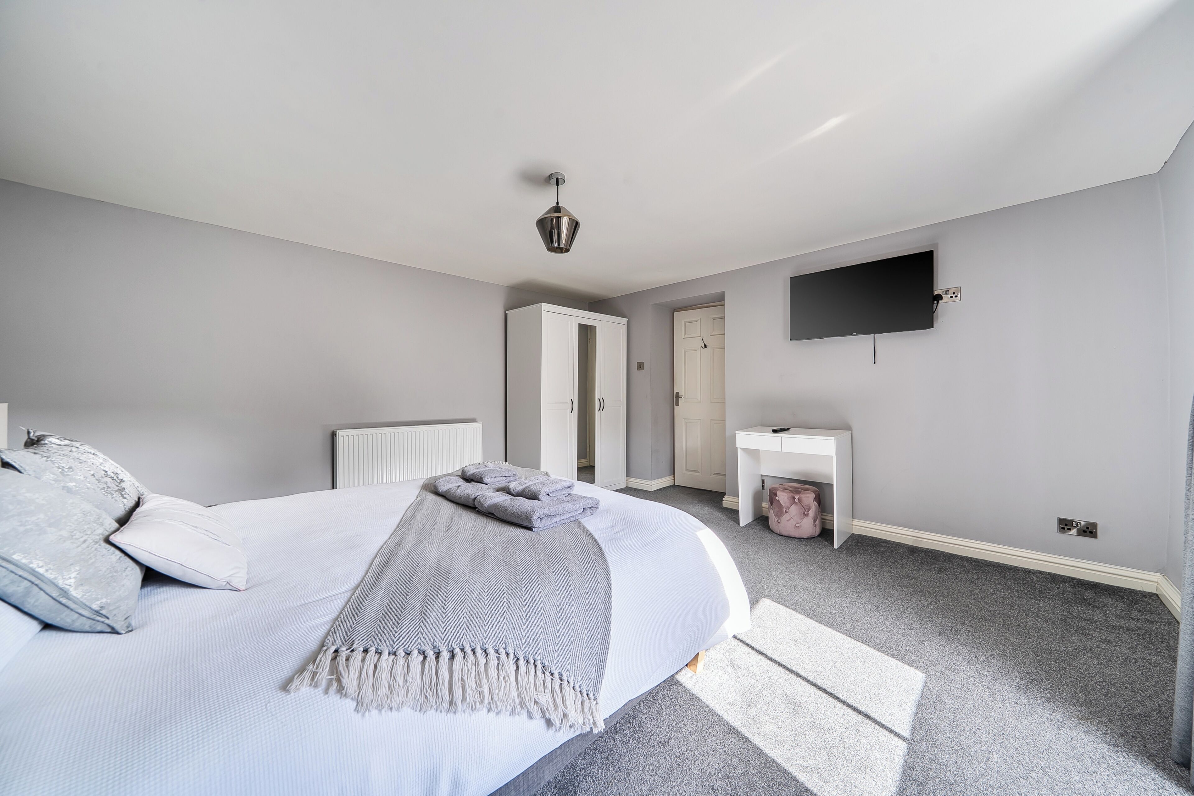 A bedroom with a bed, bedside table, and a television mounted on the wall.
