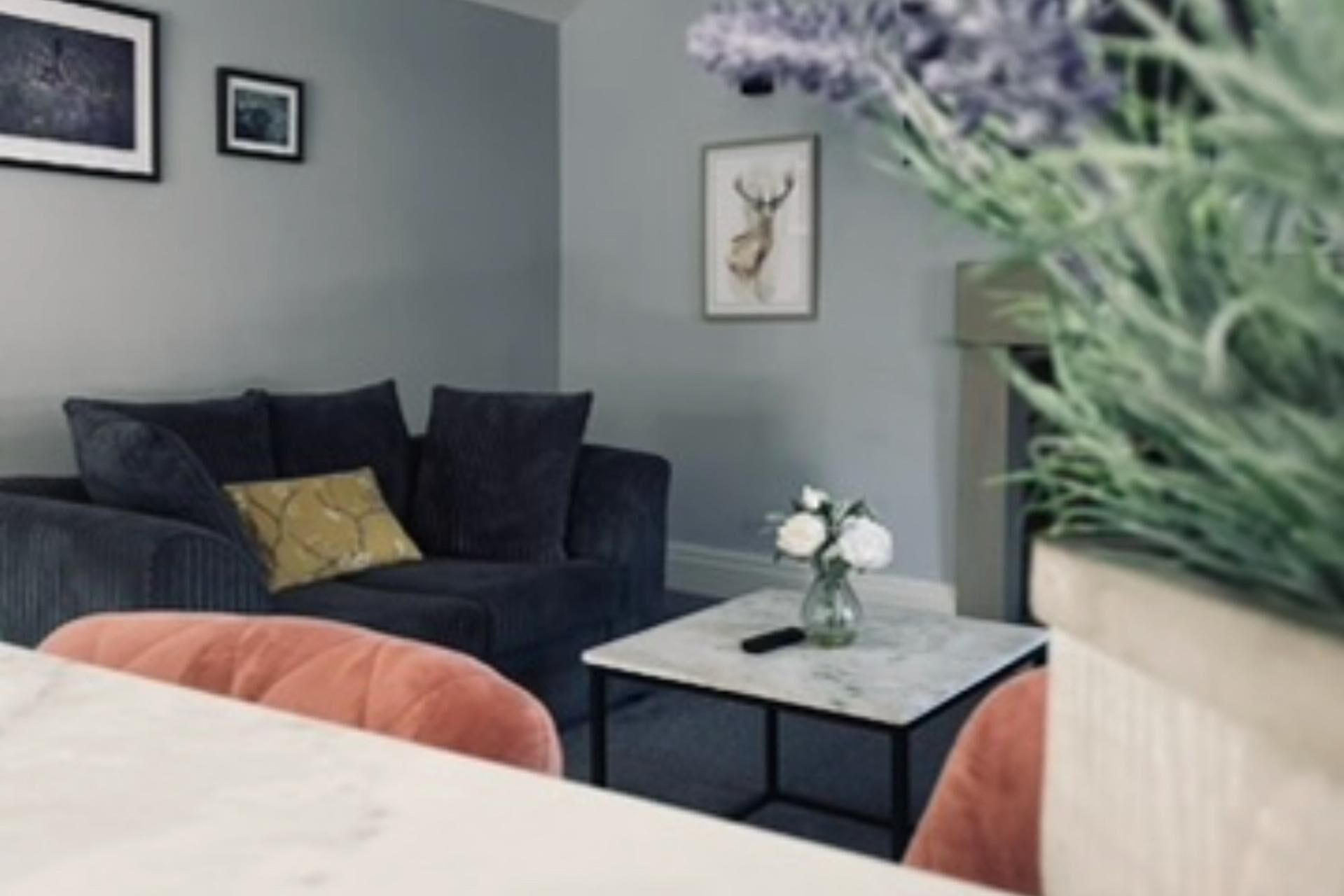 Un salon avec un canapé de couleur sombre, une petite table basse et un tableau encadré au mur.