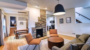 A modern living room with a fireplace, wooden flooring, a round coffee table, and a sofa.