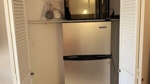 Een kleine keuken met een koelkast, een gootsteen en een klein aanrecht.