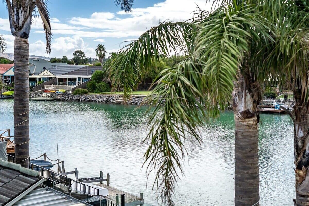 A waterfront property with a dock, palm trees, and a building with a sloped roof.