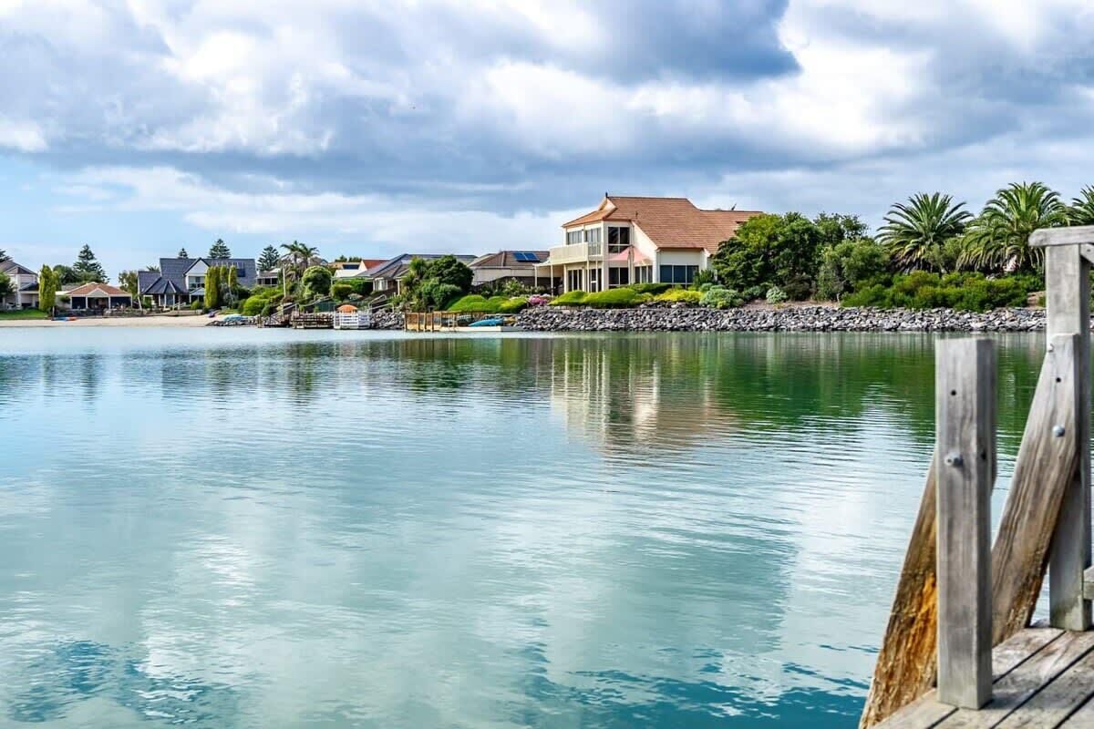 Ein Anwesen am Wasser mit Anlegesteg, Strand und einem großen Haus mit rotem Dach.