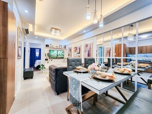 A modern dining area with a long table set for a meal, a television, and a decorative chandelier.