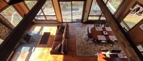 Un loft amplio con techo alto, ventanas grandes, un sofá, una mesa de comedor y una chimenea.