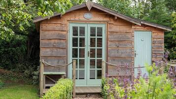 Una cabaña de madera con puerta verde, un pequeño porche y un cartel sobre la puerta.