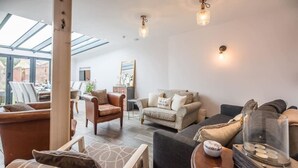 A modern living room with a glass ceiling, a sofa set, a coffee table with decorative items, and a side table.