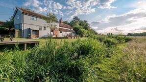 A two-story house with a wooden deck and a garden in front. - Ivy House Mells (Halesworth)