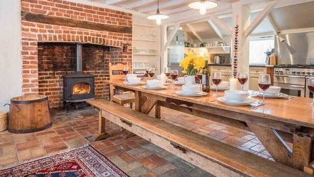 A rustic kitchen with a brick fireplace, wooden table, and benches. - Ivy House Mells (Halesworth)