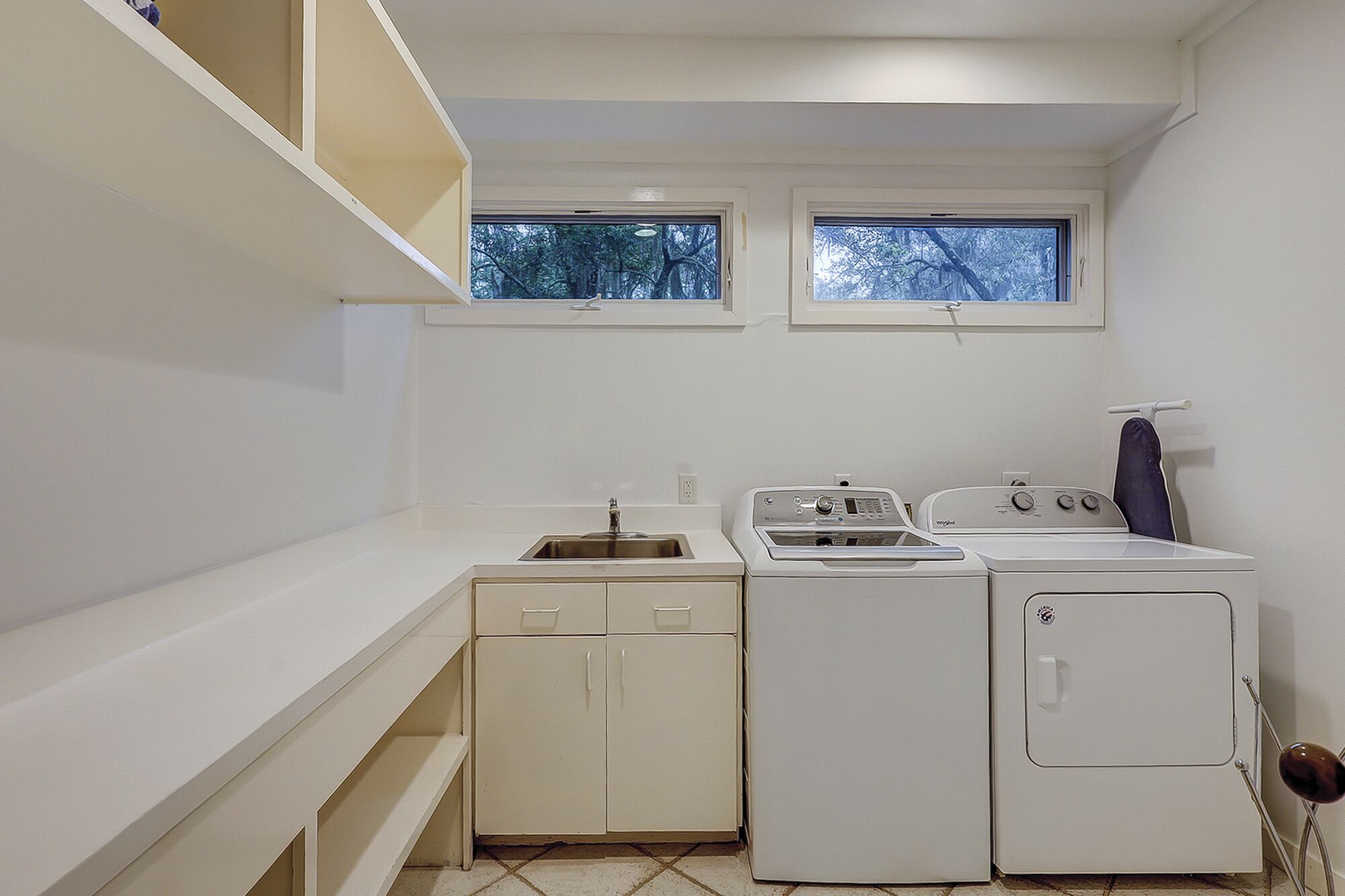 A compact laundry room with a washing machine, dryer, and sink.