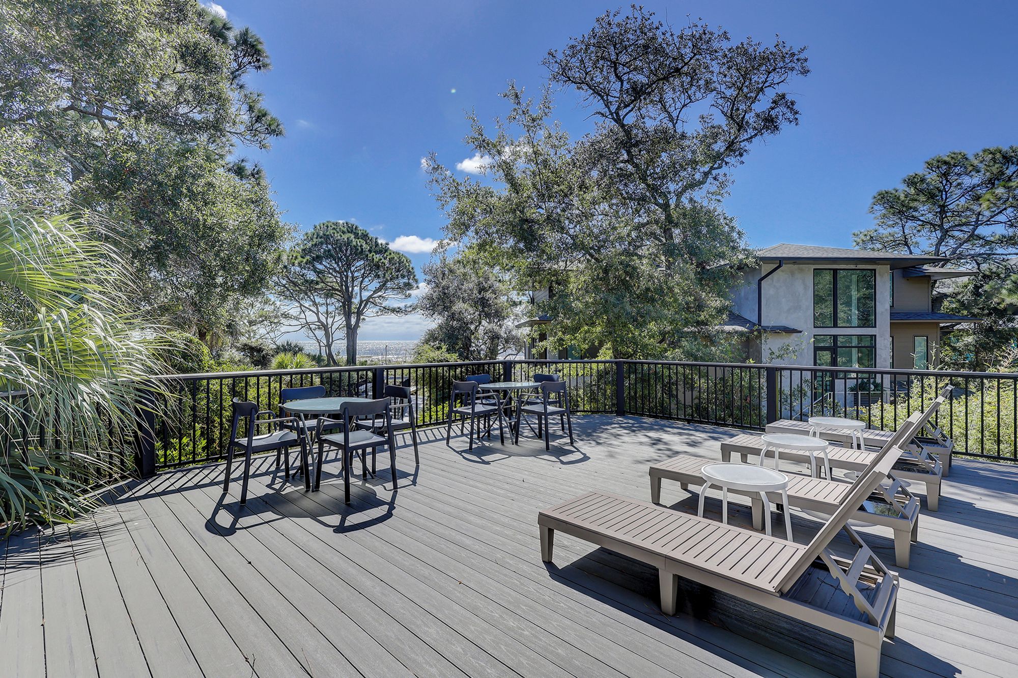 Une terrasse extérieure avec des tables et des chaises, entourée d’arbres et offrant une vue sur le paysage urbain.