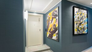 A hallway with a door labeled "CASTELLO," a staircase, and two large abstract paintings on the walls. - Sant'Ambrogio Apartments (Milan)