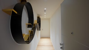 A modern hallway with a wooden floor, a large circular wall decoration, and a door at the end. - Sant'Ambrogio Apartments (Milan)