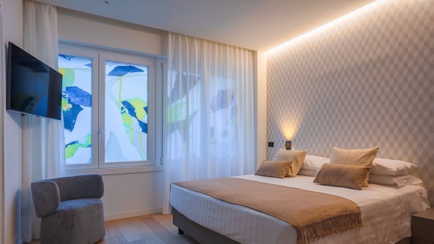 A modern bedroom with a bed, a chair, and a TV mounted on the wall. - Sant'Ambrogio Apartments (Milan)