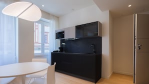 A modern kitchen with a black countertop, white chairs, and a large window. - Sant'Ambrogio Apartments (Milan)
