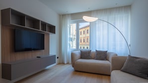 A modern living room with a flat-screen TV, a sofa, and a floor lamp. - Sant'Ambrogio Apartments (Milan)
