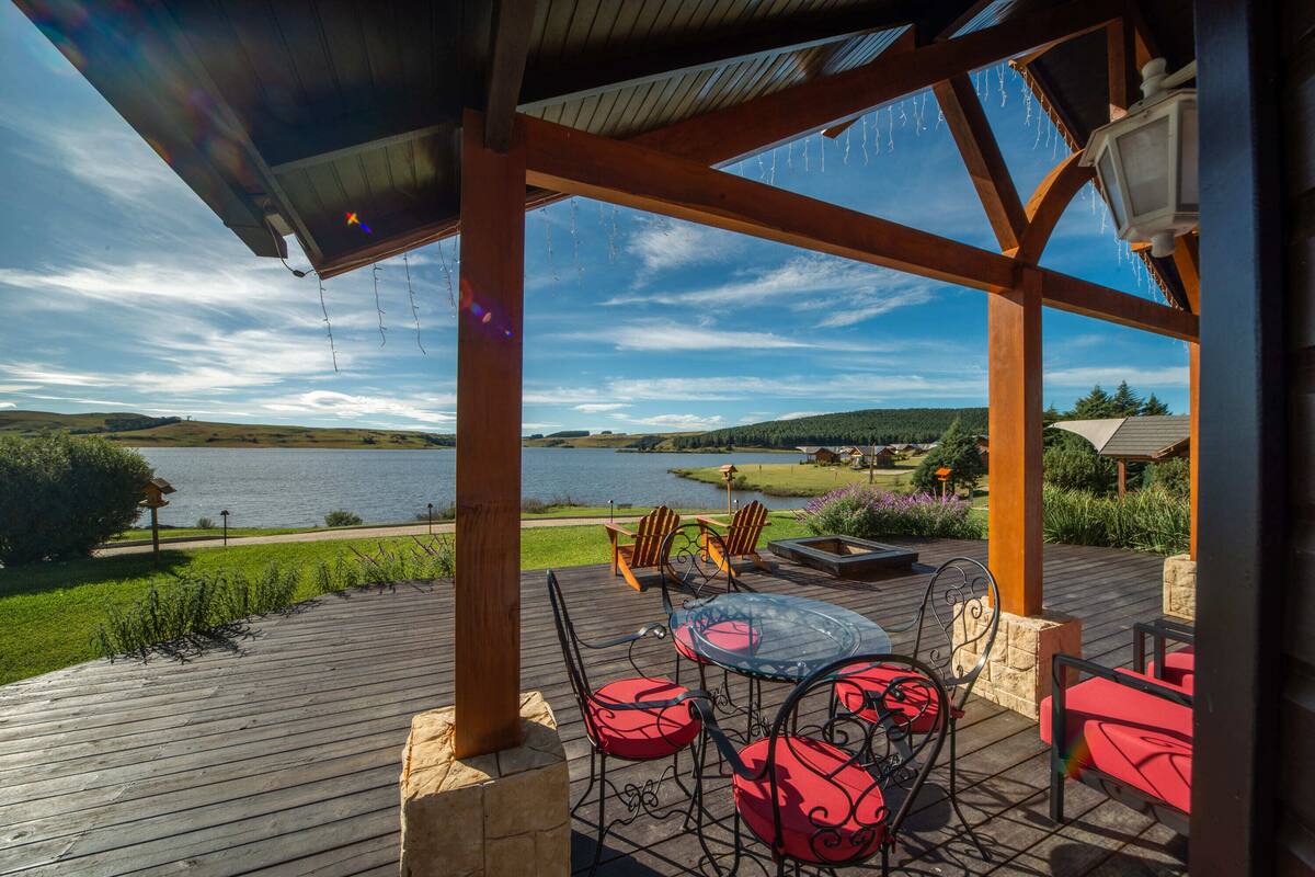 Una terraza de madera con mobiliario exterior con vista a un lago.