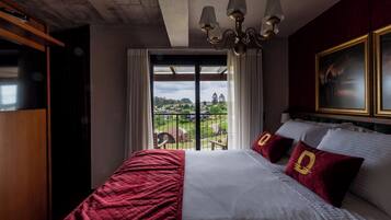 Habitación de hotel con una cama grande, una araña, vistas al exterior y un cuadro en la pared.