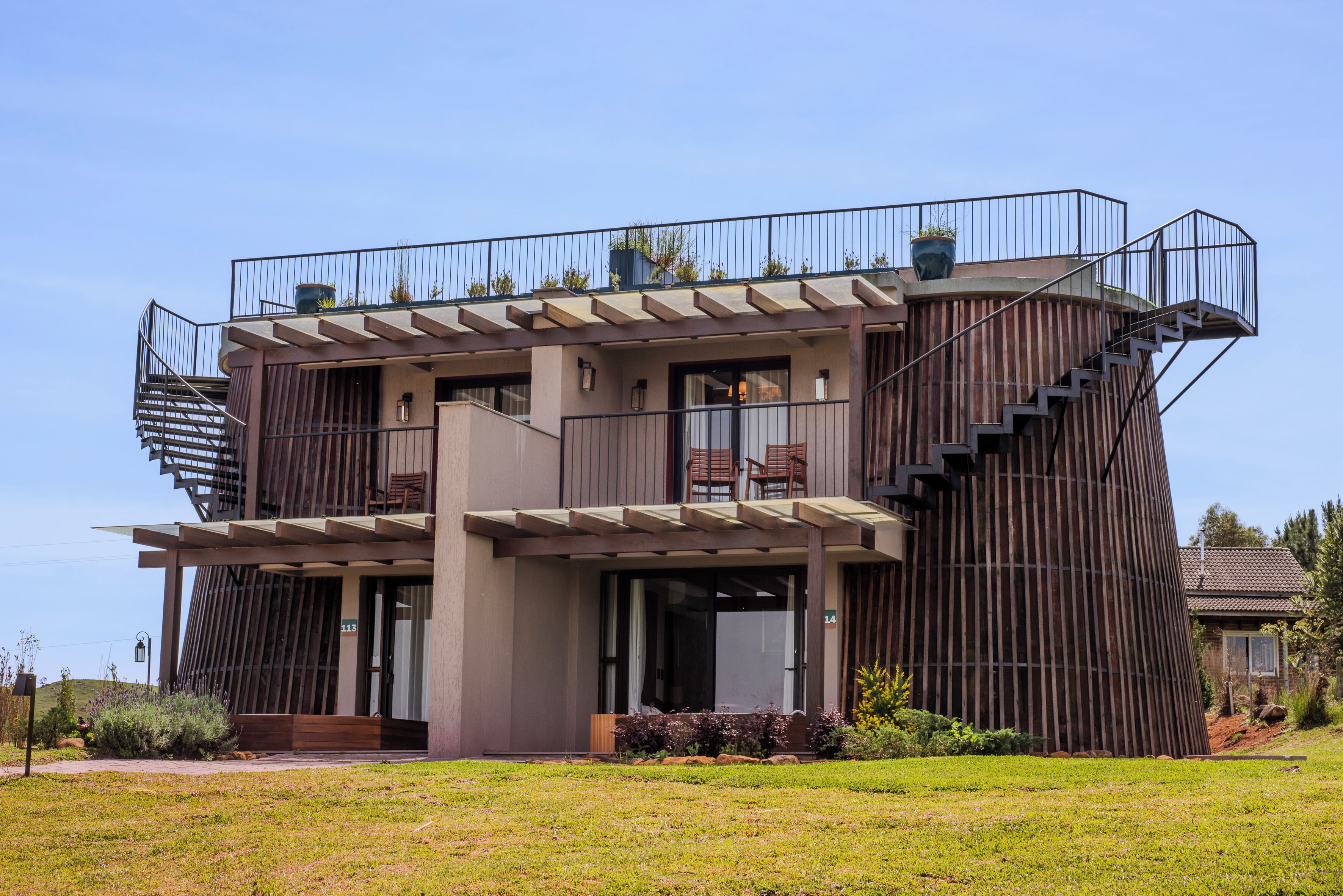 A modern multi-story building with a unique architectural design, featuring a spiral staircase and outdoor seating areas.