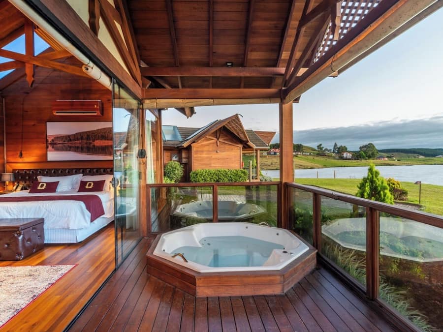 A wooden deck with a hot tub and a bedroom with a bed and a nightstand.