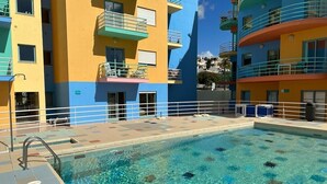 Una piscina con acqua cristallina, circondata da edifici a più piani con balconi e finestre.