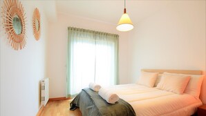 Una camera da letto con un letto, un termosifone, una finestra con tende e opere d'arte alle pareti.