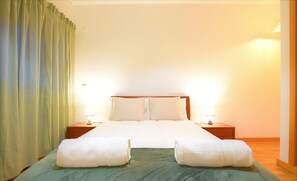 A neatly made bed with white linens, two bedside lamps, and a green rug. - 2 Bedroom Condo in Albufeira (Albufeira)