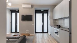 Une cuisine moderne dotée d’un four encastré, d’un téléviseur à écran plat fixé au mur et d’une porte coulissante portant l’inscription « SORTIE ».