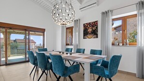 Et moderne spiseområde med et stort bord, blå stole og en usædvanlig sfærisk lampe.