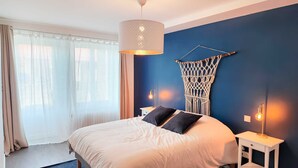 A bedroom with a bed, a macrame wall hanging, and two bedside lamps.