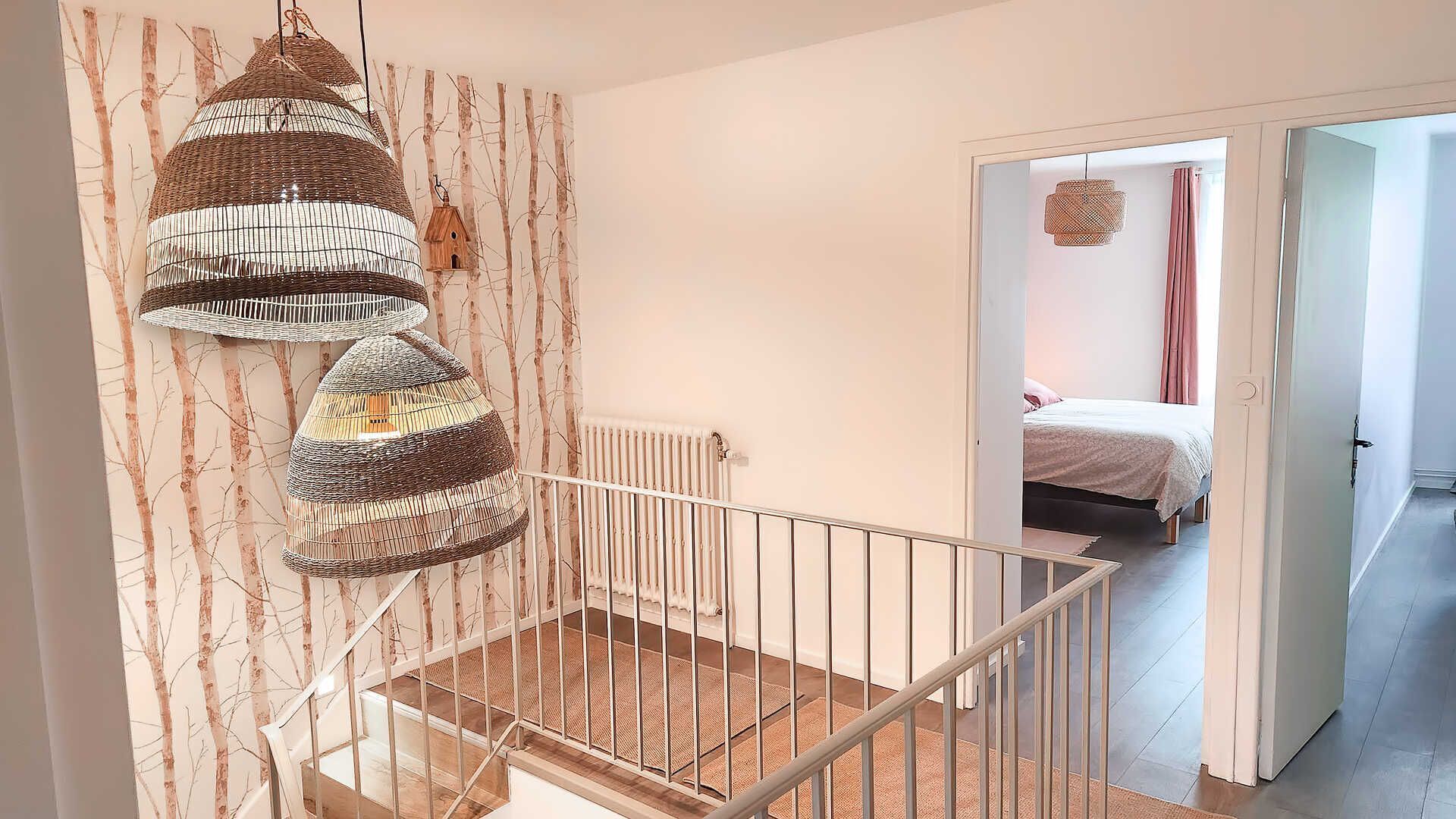 Un escalier avec une rampe blanche, menant à une chambre à coucher avec un lit et une fenêtre.