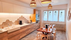 A modern kitchen with wooden cabinets, a central island, and a dining area with a table and chairs.