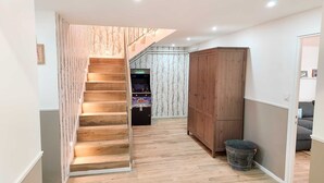 A hallway with a wooden staircase, a wardrobe, and a gaming console.