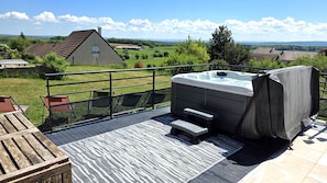 A hot tub on an outdoor deck with a view of a rural landscape.