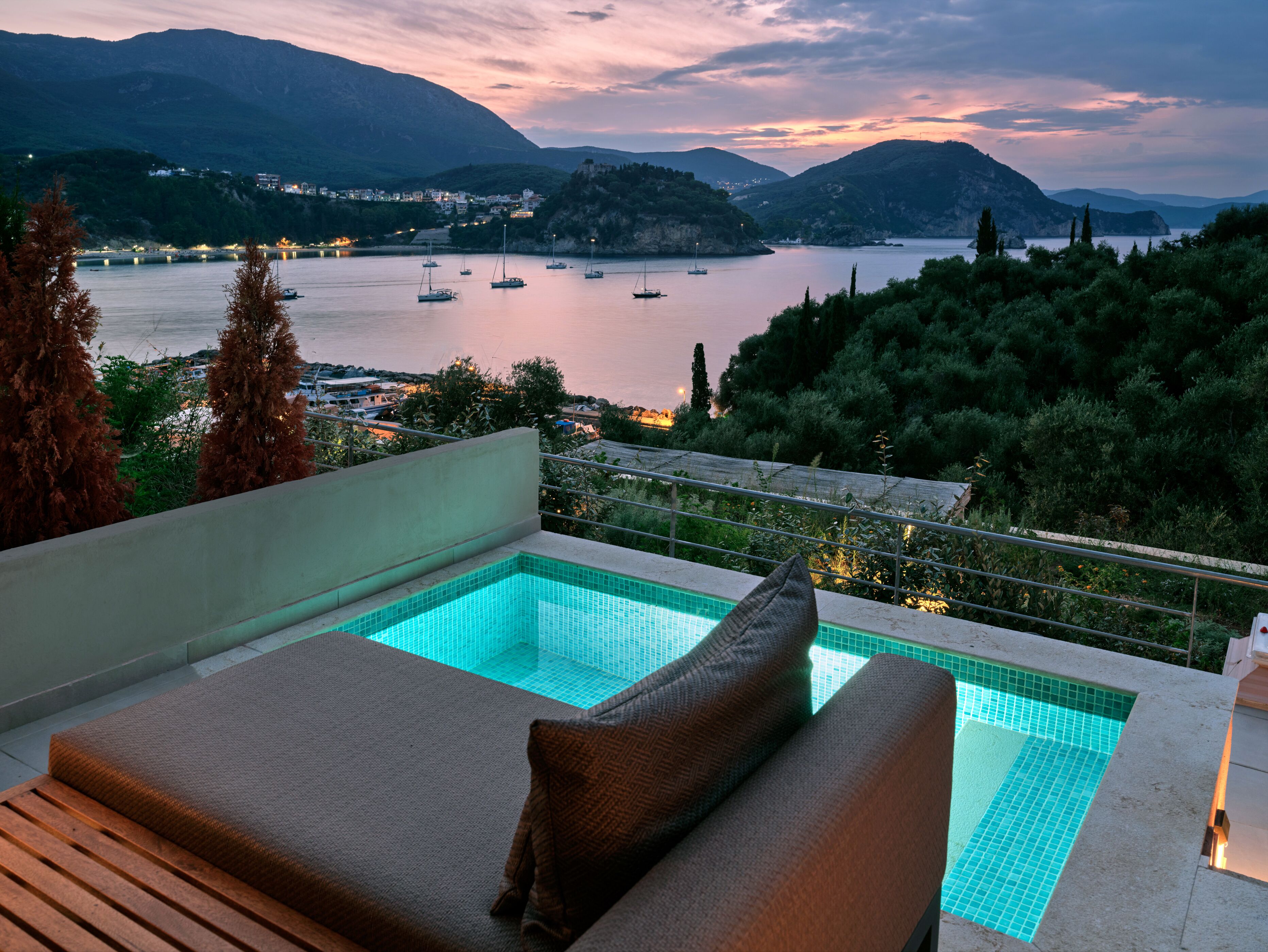 A rooftop pool with a view of boats on a lake and mountains in the background.