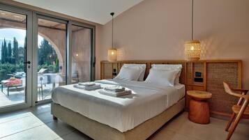 A spacious bedroom with a large bed, a wooden headboard, and a view of a garden through a sliding glass door.