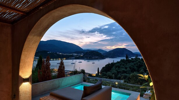 Een balkon met een zwembad, een bank en uitzicht op een meer en bergen.