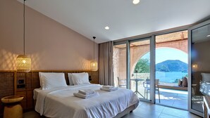Ruime slaapkamer met een groot bed, een nachtkastje en uitzicht op een balkon met zitplaatsen.